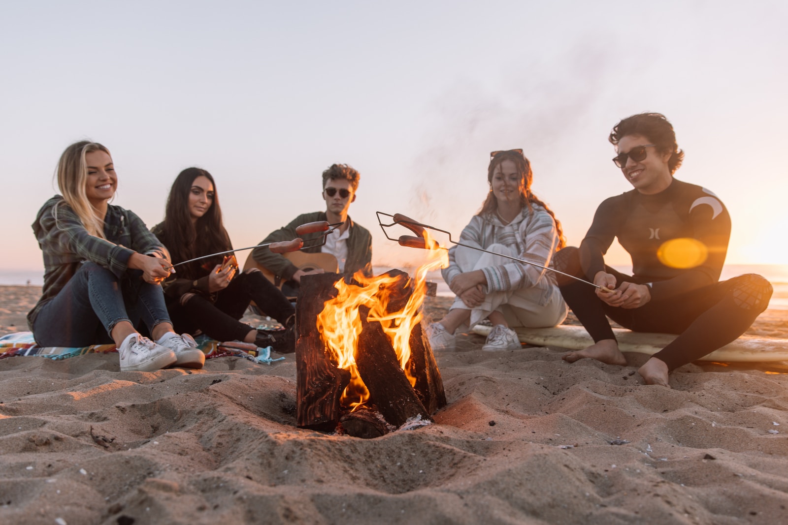 group of people sitting on ground with bonfire